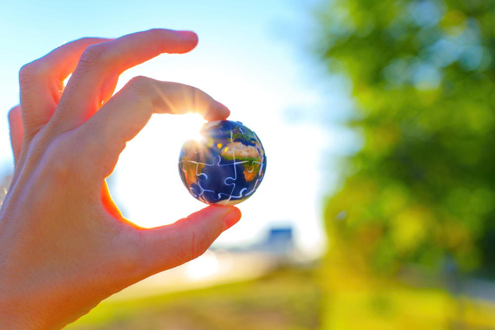 Hand hält kleine Weltkugel aus Puzzelteilen. / iStock/Ekaterina Chizhevskaya Hand hält kleine Weltkugel aus Puzzelteilen.